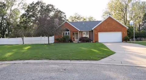 Brick, single-story house with attached two-car garage and green lawn.