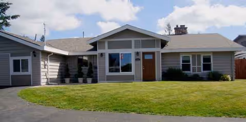 Single-story residential facility with a grassy lawn, driveway, and front entrance.