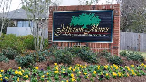 Brick sign reading Jefferson Manor Nursing and Rehab sits among landscaped flower beds.