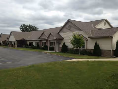 Beige senior living facility exterior with connected wings and a manicured lawn.