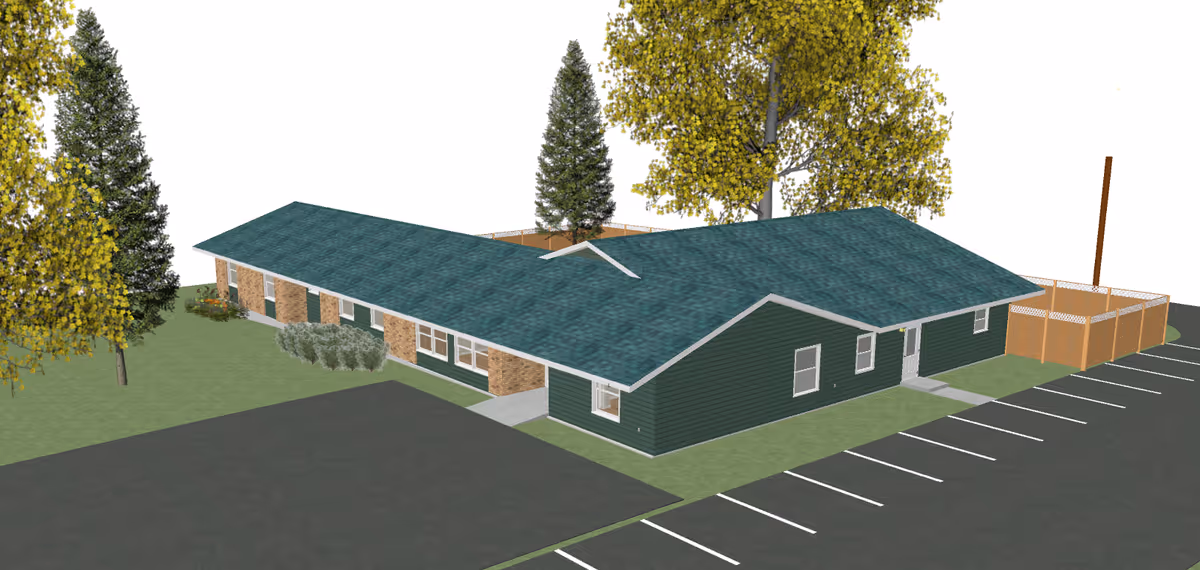 Aerial view of a single-story green building with a teal roof, surrounding trees, landscaping and an adjacent parking lot.