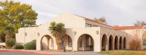 Exterior view of Rio Rancho Center senior living facility with arches and palm trees.