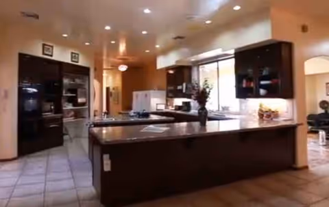 Interior kitchen in Via Elegante Mediterranean with island and dark cabinets.