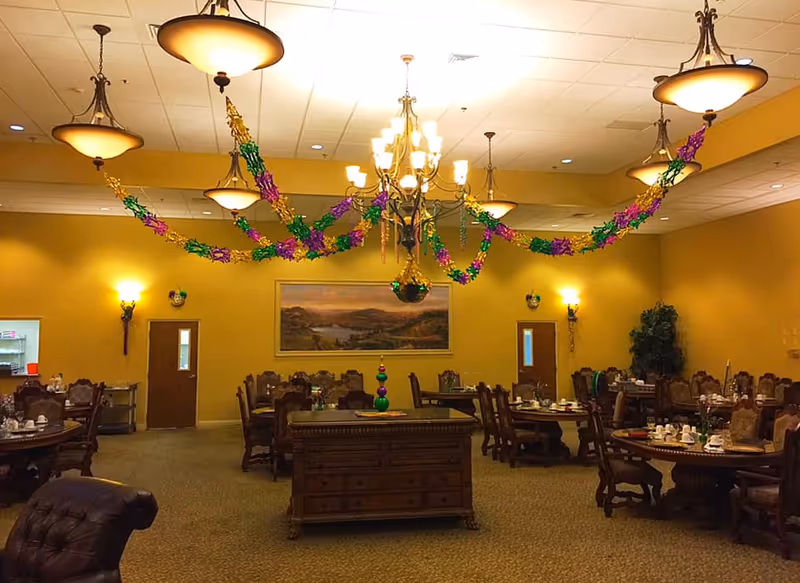 Dining room with chandeliers, festive garlands, and multiple set dining tables.