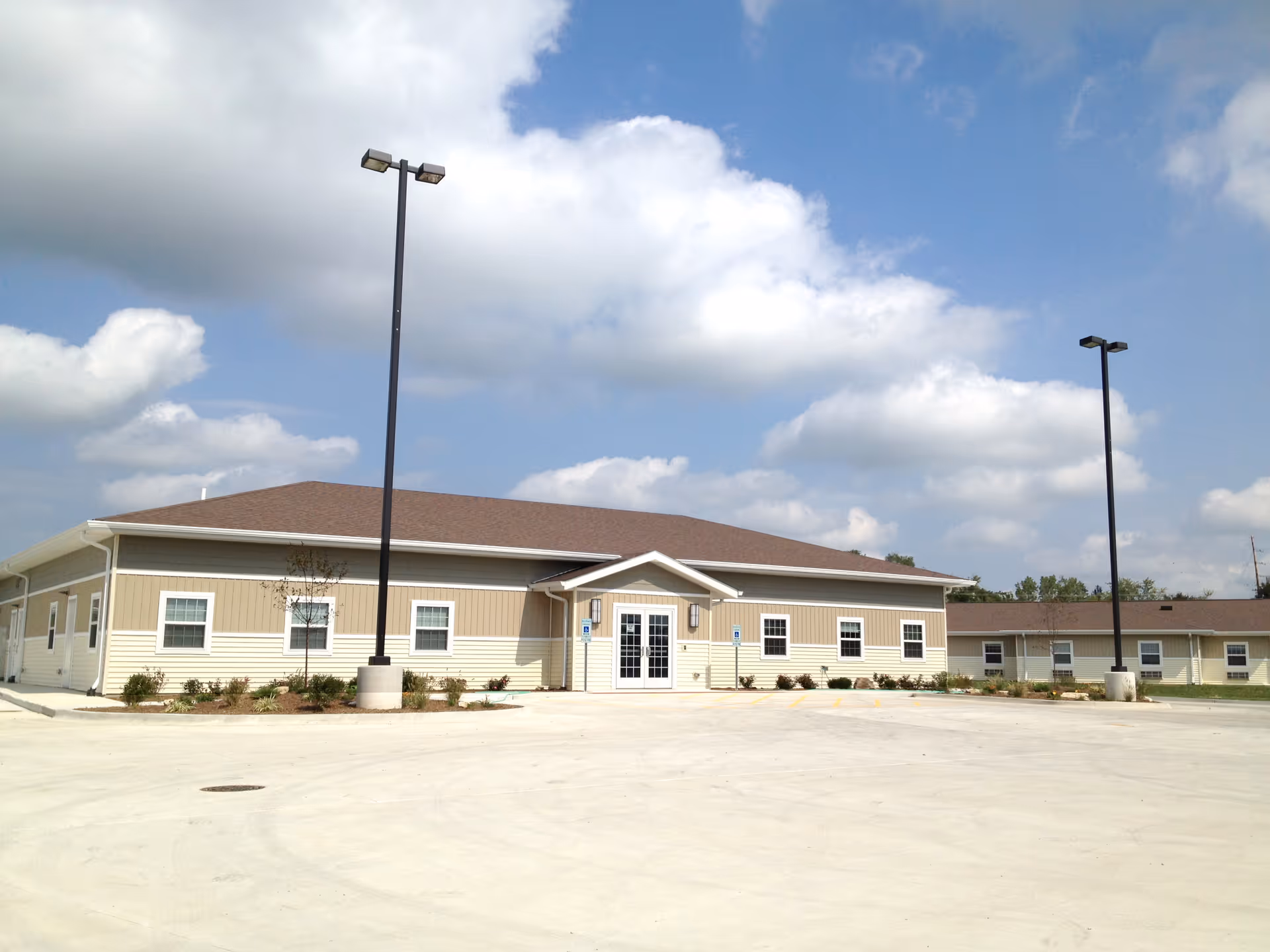 A view of the Heritage Health senior living facility with a large parking area and clouds in the sky.