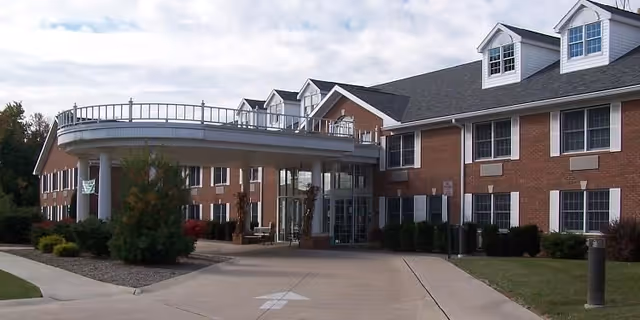 Exterior view of The Woodlands of Liberty Assisted Living with curved entrance and brick facade.