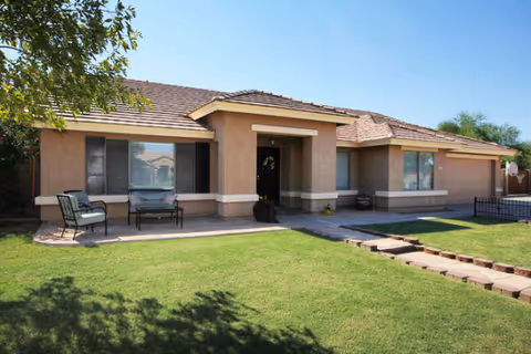 Single-story beige stucco building with front porch and a green lawn.
