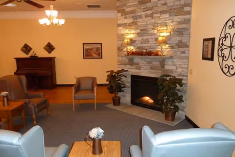 Cozy lounge with a fireplace, chairs, and a coffee table in a warm senior living space.