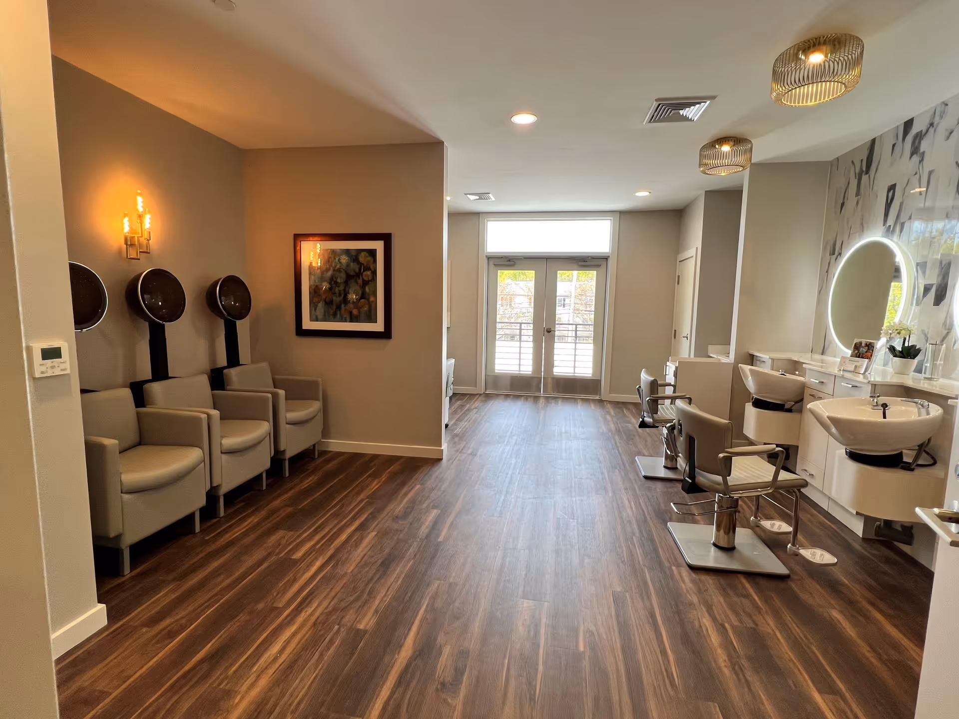 Bright modern salon with hair-washing sinks, styling chairs, and waiting seats along a wall.