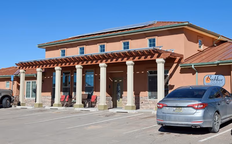 BeeHive Homes Assisted Living building exterior with a covered entrance and parked cars in front.