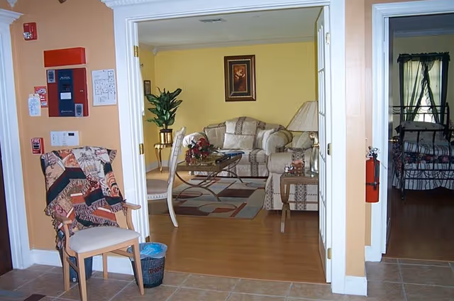 View through a doorway into a cozy living room with upholstered sofas, a glass coffee table, and a decorative rug.