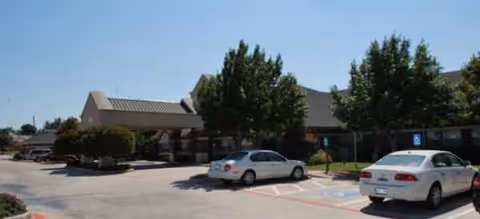 Brookdale Summer Ridge exterior with parked cars and trees in front of the building.