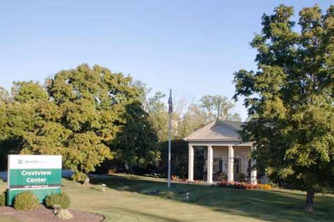 Exterior view of Crestview Center with sign, lawn, and front entrance columns.