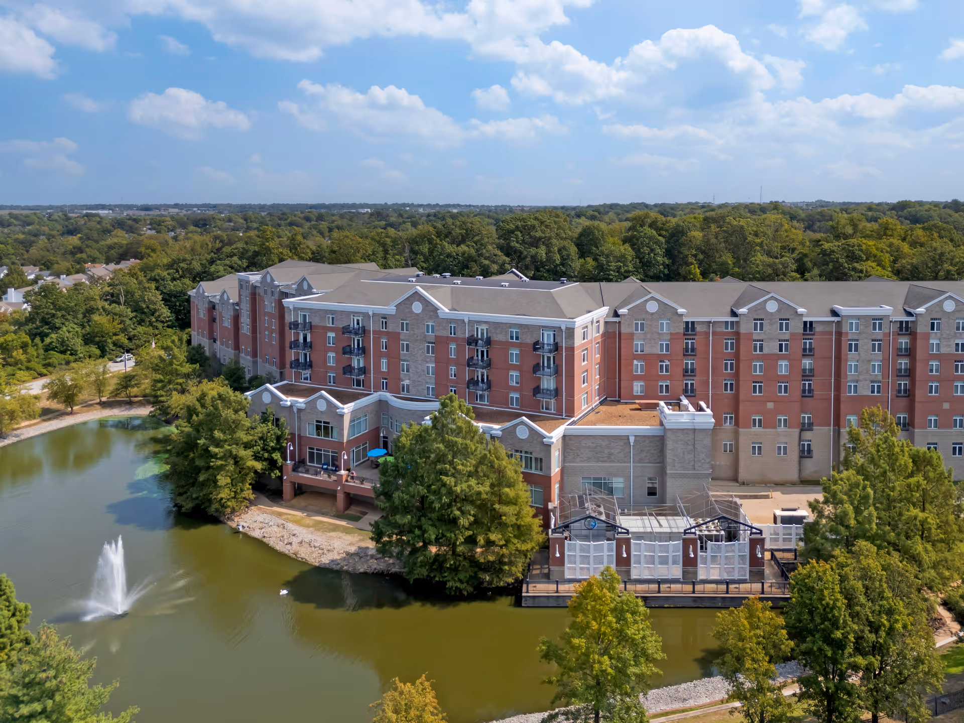Exterior view of Brookdale Creve Coeur, a large brick senior living campus beside a pond.