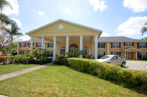 Two-story beige senior living building with white columns and a front porte-cochere.