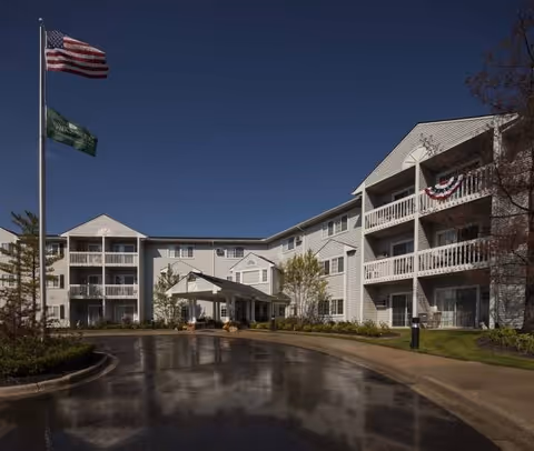 Waltonwood Carriage Park exterior: white multi-story building, flags, and covered entrance.