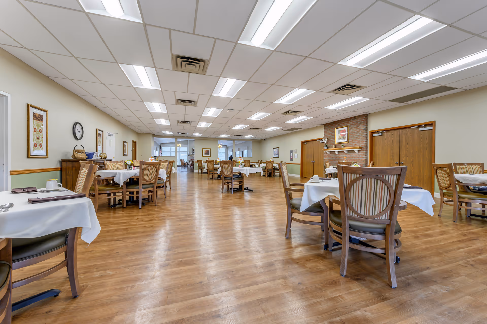 Spacious dining room with multiple tables and chairs set with white tablecloths and place settings.