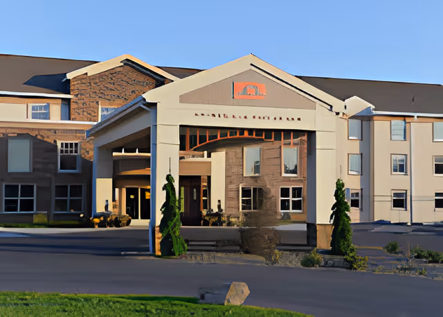 Front exterior view of Poplar Run a StoneRidge Retirement Living Community building with a covered entrance and some greenery around the driveway.