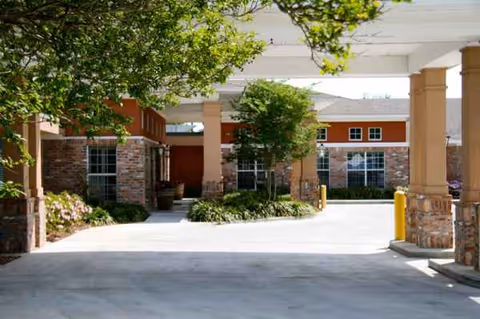 Exterior view of Belle Teche Nursing & Rehabilitation Center entrance with pillars and trees.
