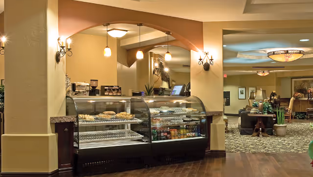 Interior common area with a glass pastry and beverage display case and a seating/lounge area beyond.