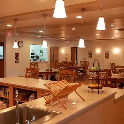 Open kitchen counter overlooking a communal dining room with wooden tables and hanging pendant lights.