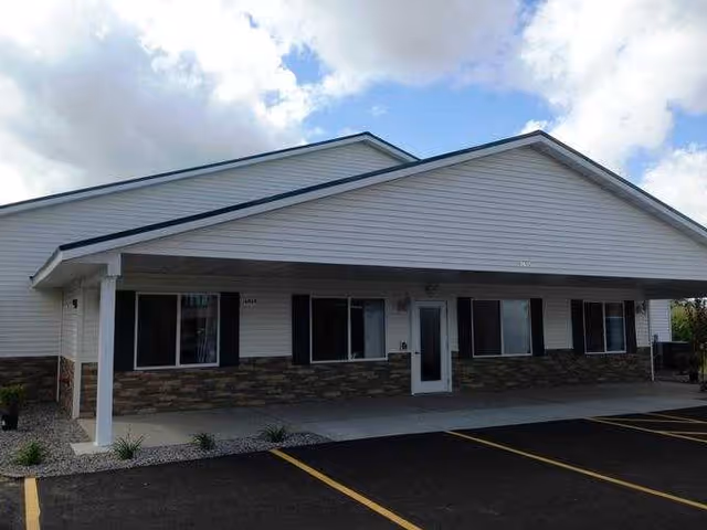 Front view of a Care Partners Assisted Living building featuring a covered entrance and parking.