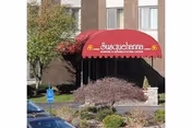 Red scalloped entrance awning reading 'Susquehanna Nursing & Rehabilitation Center' over the landscaped front driveway of a brick building.