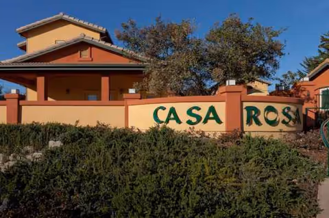 Exterior view of Casa Rosa Elder Care sign and entrance with shrubs.
