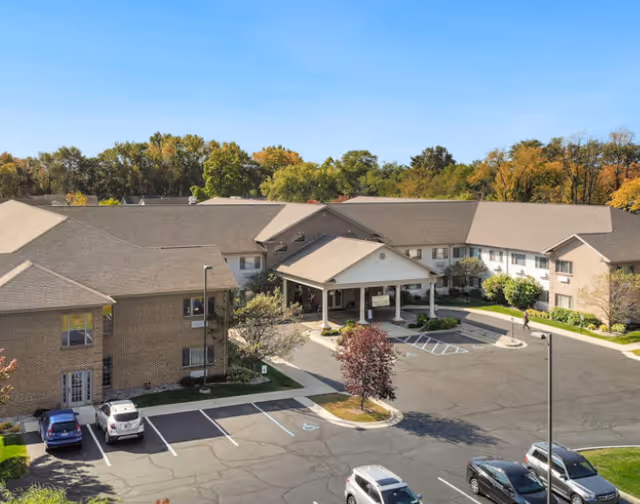 A multi-building senior living campus with a covered entrance, parking lots, and surrounding trees.