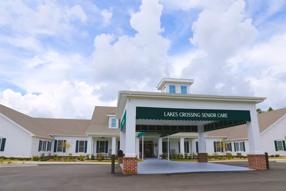 Front entrance of Lakes Crossing Senior Care building with a covered porte-cochere and green awning bearing the facility name.
