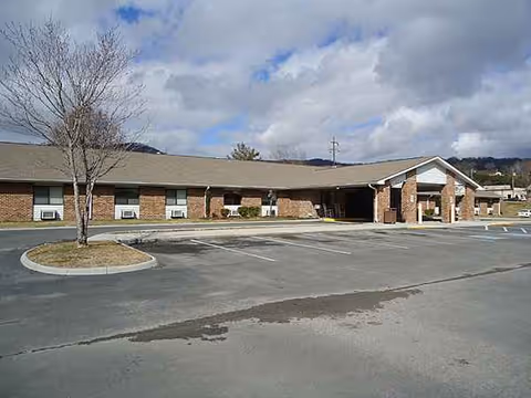 Single-story brick senior living facility with a covered entrance and parking lot.