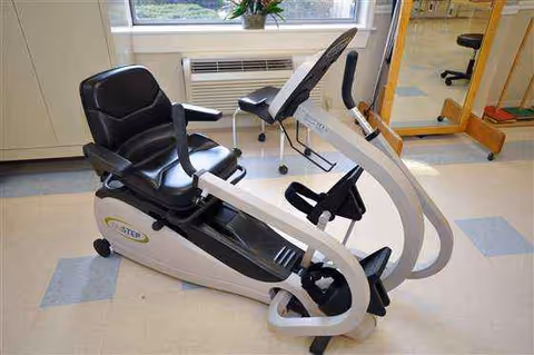 White stationary exercise bike with black seat in a bright tiled interior room.