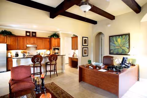 Spacious senior living common area with a kitchen island, bar stools, and a reception desk.