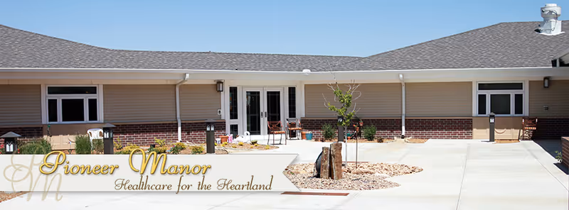 Front exterior of a single-story senior living facility with a paved courtyard and main entrance.