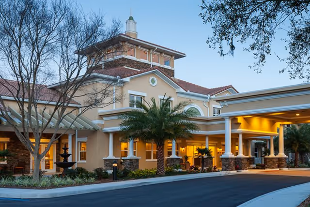 Senior living facility exterior with a covered entrance and palm trees.