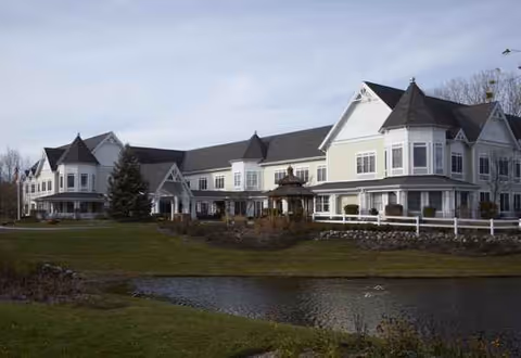 Exterior view of Sunrise of Gurnee senior living facility with a pond and manicured grounds