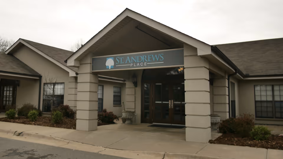 Covered front entrance of a single-story care facility with double doors and a 'St. Andrews Place' sign.