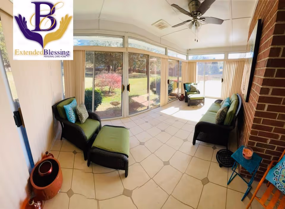 Bright enclosed sunroom with wicker seating and green cushions, tiled floor, ceiling fan, and sliding glass doors looking out to a garden.