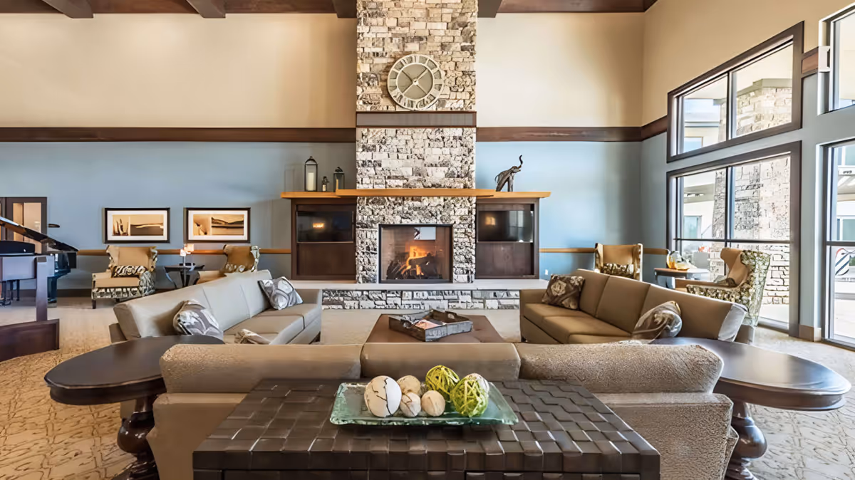 Spacious lounge with sofas arranged around a central stone fireplace and large windows.
