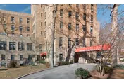Exterior view of a brick senior living facility with a red awning entrance.
