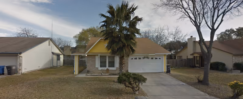 Front exterior of a single-story suburban house with a two-car garage and a palm tree in the yard.