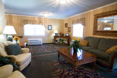 Cozy senior living room with sofas, a wooden coffee table, lamps, and patterned carpet.