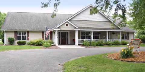 Front view of a single-story senior living facility with a porch and landscaping.