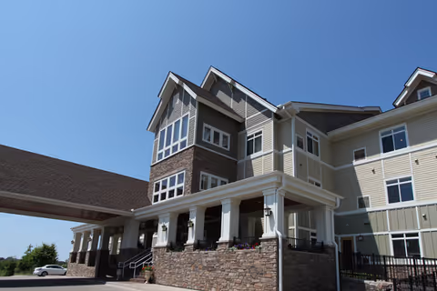 Exterior of a multi-story senior living facility with a stone base and porch.