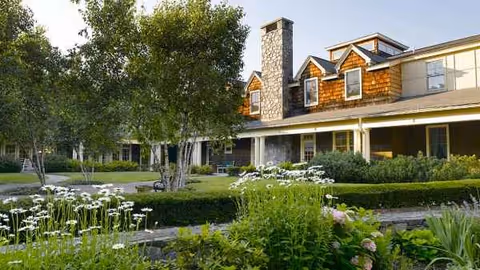 Atria Darien exterior building with brick siding, trees, and blooming garden.