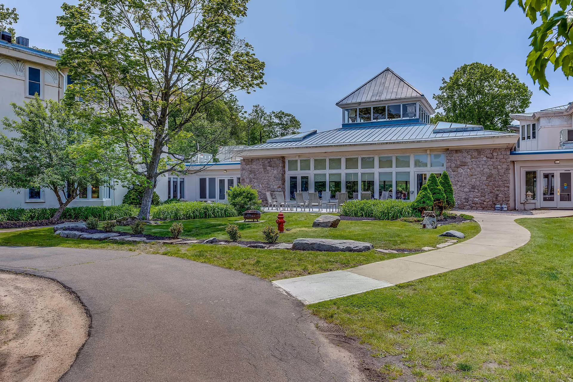 Front exterior of the Guilford Retirement Residence showing the building, lawn, trees, and a curved walkway.