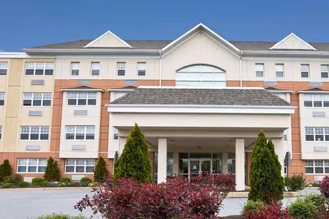Exterior view of Ashbridge Manor senior living building with a covered entrance and landscaping.
