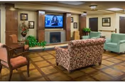 Cozy communal living room with a sofa, armchairs, a fireplace and a wall-mounted TV.