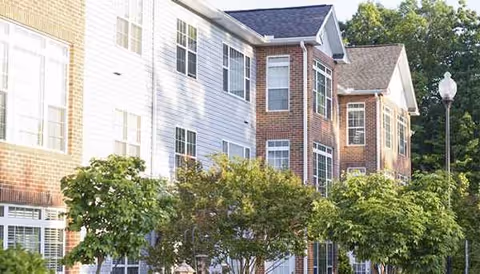 Exterior view of a senior living residential apartment building with trees.