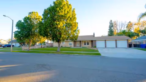 Single-story senior living facility front with manicured lawn and trees.